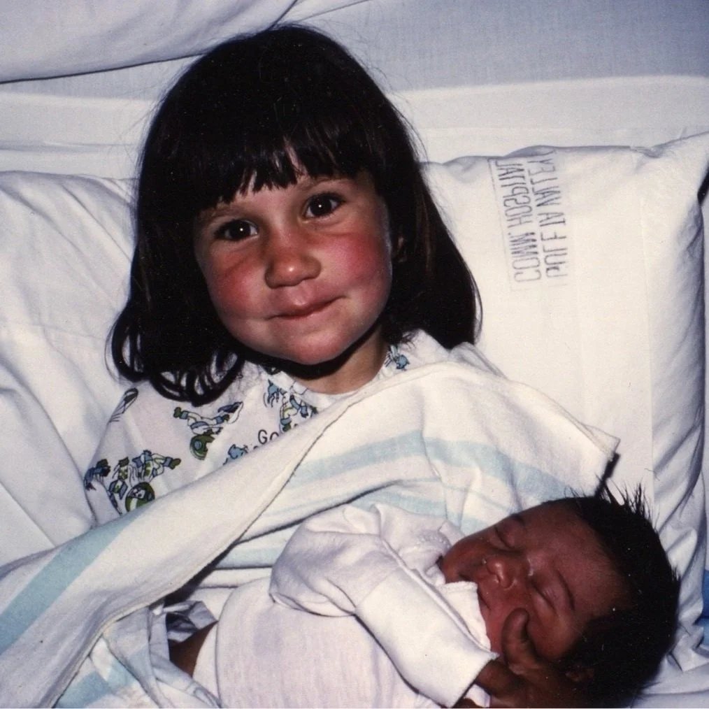 Mimosa as a child holding her baby brother